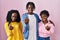 Group of three young black people standing together over pink background beckoning come here gesture with hand inviting welcoming