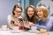 Group of three young women smiling and showing the pictures on the smartphones each other, sitting in restaurant