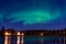 Group of Tipi under Aurora Borealis with smooth water reflection