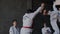 Group of titul taekwondo male sportsmans perform spectacular original fight stance. Guys break and crash wooden plate in