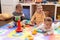 Group of toddlers playing with toys sitting on floor at kindergarten