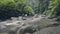 Group tourist people walking on rocks of mountain river flowing in rainforest. Drone view people traveling on stony