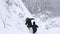 A group of tourists descends from the top of a snow-covered mountain.