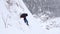 A group of tourists descends from the top of a snow-covered mountain.