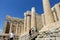 A group of tourists entering the Acropolis walking through the massive marble doric columns on a hot sunny summer day in Athens