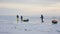 Group of tourists with equipped sledges trek besides gray frozen ice hummocks
