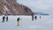 Group of tourists exploring magnifficent frozen coast using nordic ice skates with poles. Drone shot of well equipped