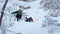 A group of tourists rises to the top of a snow-covered mountain.