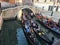 A group of tourists sitting in three gondolas side by side at a gondola boarding area in Venice, Italy.