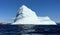 A group of tourists on a tour boat viewing a massive and spectacular iceberg off the coast of Twilingate