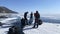 A group of tourists travels on ice skates on the ice of the frozen Lake Baikal