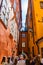 Group of tourists walking by cozy vibrant narrow medieval street with connected yellow orange red buildings facades in Gamla stan