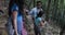 Group Of Tourists Walking Down Hill In Forest Trekking, People On Hike Friends Hikers Helping Each Other