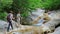 A group of tourists walks along the bottom of the canyon along a clean mountain river.