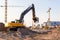 Group tower cranes and excavator silhouette at construction site, sunset sky background