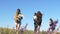 A group of travelers with backpacks, mom and daughters, a small child, in summer travels across a field with flowers