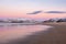 A group of travelers in the distance on the beach. Beautiful pink sunset on the Arctic Ocean. A peninsula with snow-capped hills