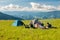 Group of trekkers hikers camping on grass meadow with view of Maramures ridge from Rodna Mountains, Muntii Rodnei National Park,