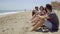 Group of trendy young friends sitting on a beach