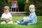 Group of two white Caucasian toddler children kids boy and girl sitting outside in grass in summer autumn park