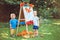 Group of two white Caucasian toddler children kids boy and girl standing outside in summer autumn park by drawing easel