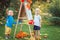 Group of two white Caucasian toddler children kids boy and girl standing outside in summer autumn park by drawing easel