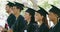 Group of university or college graduates in mortarboards and gowns standing in a line at their graduation ceremony