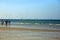 Group of unrecognizable people and flock of birds in search of fish, when the fishermen return, Qurum beach, Muscat, Oman