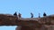 Group of unrecognizable tourists walking over a natural rock bridge