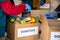 Group of unrecognizable volunteers busy working by arranging vegetables and clothes on donation boxes during coronavirus covid-19