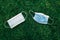Group of used and fresh sanitary masks lying on grass. Disposable recyclable face mask flat lay. Coronavirus, medicine, seasonal