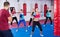 Group of vigorous females and their trainer are boxing in gym