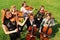 Group of violinists play standing on grass