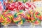 Group of vivid coloured sugar lollipops in display for sale at a candy store in individual plastic packaging, selective focus