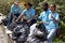 Group of volunteers in blue t-shirt holding garbage bag at rubbish dump, ecology people cleaning and picking up trash to reduce