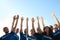 Group of volunteers raising hands on sunny day