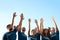 Group of volunteers raising hands on sunny day