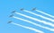 Group of white turboprop aircraft with a trace of white smoke against a blue sky.