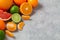 Group of whole and sliced citrus fruits - tangerines, lemons, limes, oranges, grapefruits on the surface of the gray