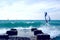 Group of windsurfers on boards in wavy sea with pier on coast