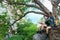 Group women hiker with backpack on big tree checks map to find directions and look binoculars in wilderness area forest,