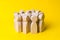 Group of wooden people figurines on a yellow background. Crowd,