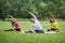 A group of yoga sportsmen performs breathing exercises in park