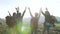 Group young active successful people raising hands on mountain top. Hikers with arms raised on top of mountain. Hikers