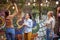 Group of young adult caucasian women setting up hanging bulbs on branches in the garden, preparing for party