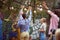 Group of young adult caucasian women setting up hanging bulbs on branches in the garden, preparing for party