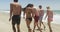 Group of young adult interracial friends strolling the beach together