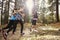 Group of young adult women running in a forest, back view