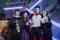 Group of young Asian friends dressed as witch, priest, vampire and nun smiling and holding drink at Halloween party