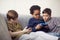 Group Of Young Boys Gaming Together On Hand Held Devices At Home